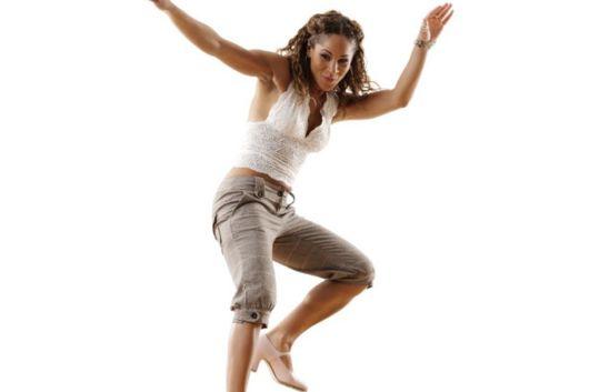 Women dancing with one high foot and arms up in the air. She is tapdancing
